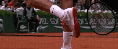 A Tennis Player Wearing Nike Socks Is Holding A Tennis Racquet On A Court GIF