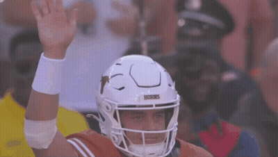 A Texas Football Player Wearing A White Helmet Holds His Hand Up GIF
