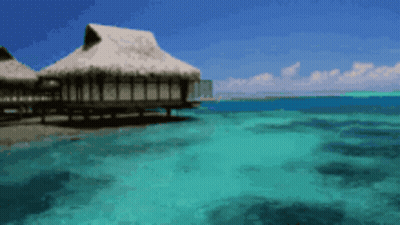 A Thatched Hut Sits On A Dock In The Middle Of The Ocean GIF