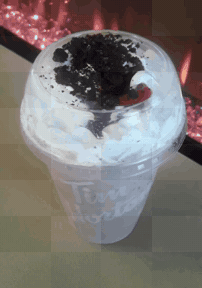 A Tim Hortons Cup With Whipped Cream And Oreo Cookies On Top GIF