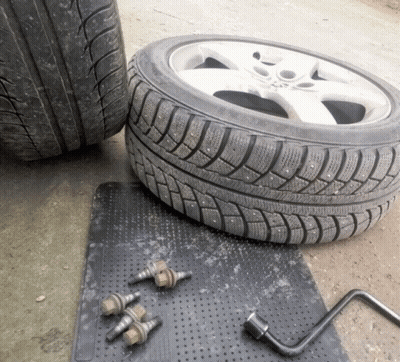 A Tire Is Sitting On A Black Mat Next To A Wheel Wrench GIF
