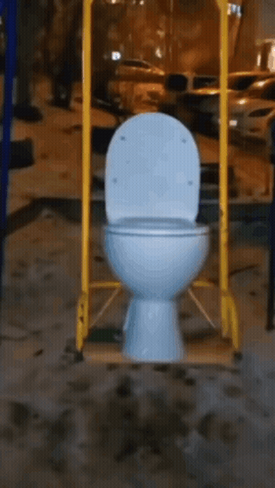 A Toilet Is Hanging From A Yellow Pole In A Playground . GIF