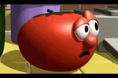 A Tomato From The Veggie Tales Cartoon Is Sitting On A Table . GIF