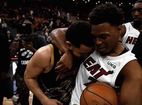 A Toronto Raptors Player Is Hugging A Heat Player GIF
