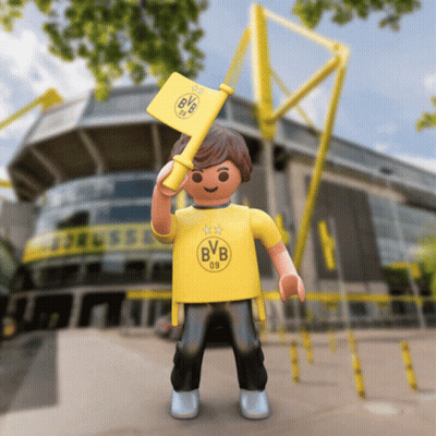 A Toy Boy Wearing A Yellow Bvb Shirt Holds A Yellow Flag GIF