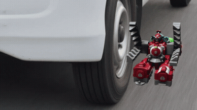 A Toy Robot Is Attached To The Side Of A Car GIF