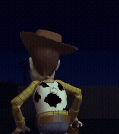 A Toy Story Woody Doll Is Standing In The Dark With His Arm Outstretched . GIF