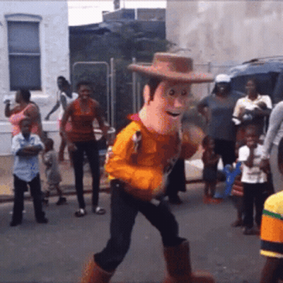 A Toy Story Woody Mascot Walking Down A Street GIF