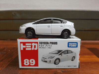 A Toy Toyota Prius Is Sitting On Top Of A Takara Tomy Box GIF