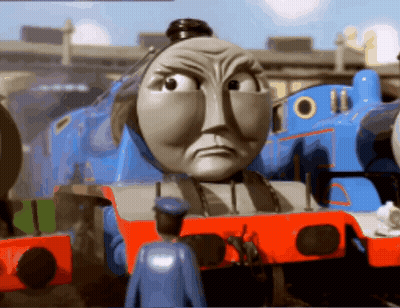A Toy Train With A Very Angry Face And A Man In A Blue Uniform Standing Next To It GIF