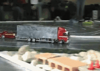 A Toy Truck Is Driving Down A Road Next To A Car GIF