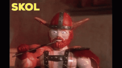 A Toy Viking With A Sword In His Mouth And The Word Skol In Yellow Behind Him GIF
