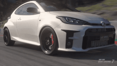 A Toyota Yaris Is Driving Down A Road In A Video Game Called Gran Turismo 7 GIF