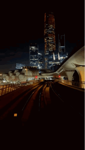 A Train Going Through A Tunnel At Night With A City In The Background GIF