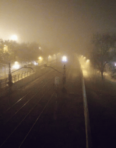 A Train Is Going Down The Tracks In A Foggy Area GIF