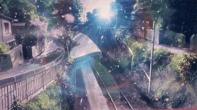 A Train Is Going Down The Tracks With Flowers Falling From The Trees . GIF