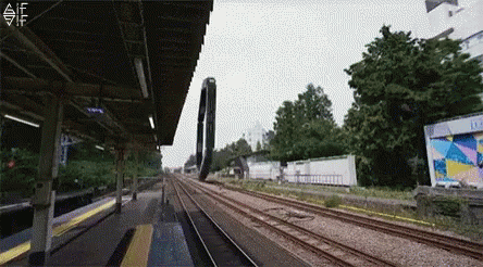 A Train Is Going Down Train Tracks At A Station . GIF