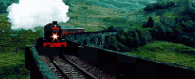 A Train Is Going Over A Bridge In The Mountains . GIF