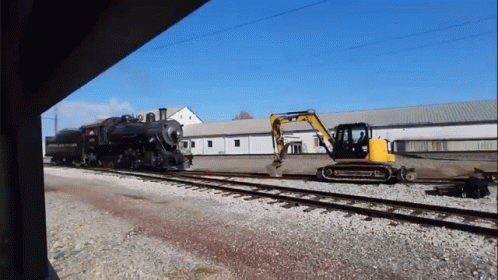 A Train Is On The Tracks With A Yellow Excavator In Front Of It GIF