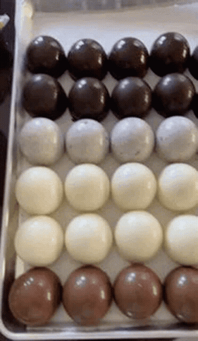 A Tray Of Chocolate Balls Of Different Flavors And Colors . GIF