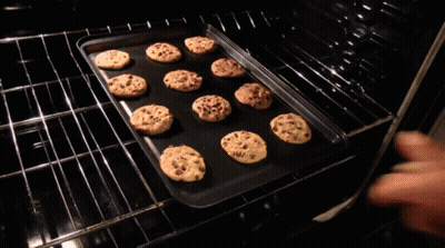 A Tray Of Chocolate Chip Cookies Is Being Pulled Out Of An Oven GIF