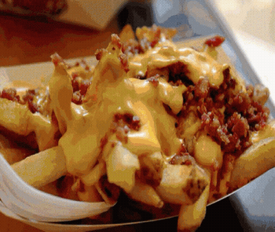 A Tray Of French Fries With Cheese And Bacon On Them GIF