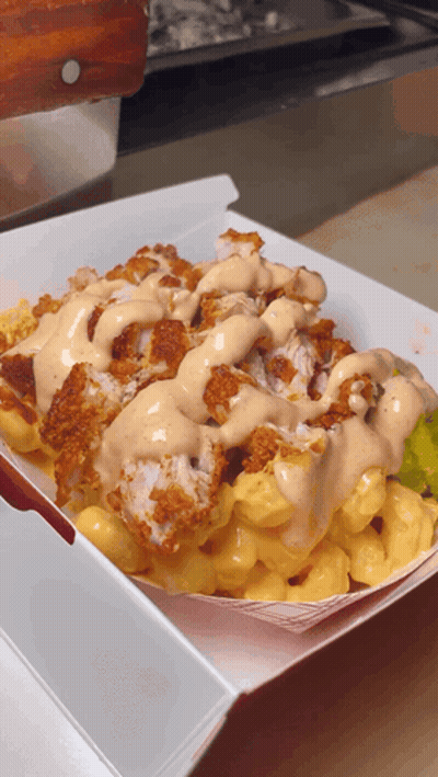 A Tray Of Macaroni And Cheese With Fried Chicken And Ranch Dressing GIF