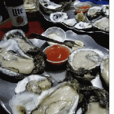 A Tray Of Oysters With Sauce And A Bottle Of Lite Beer GIF