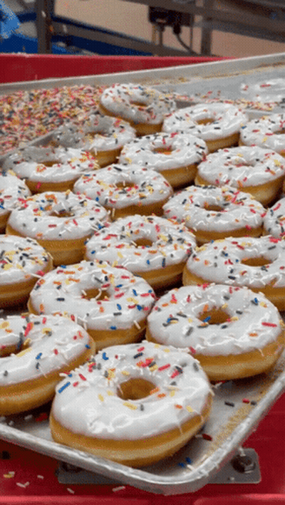 A Tray Of White Frosted Donuts With Sprinkles GIF