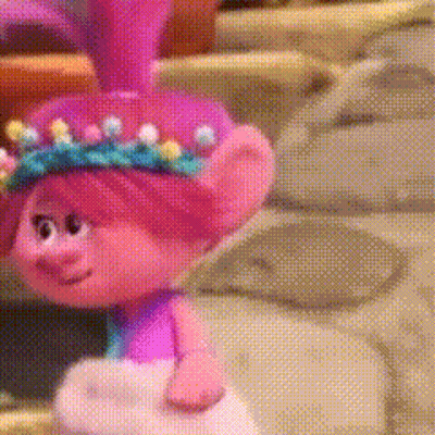 A Troll Doll With Pink Hair And A Crown Of Flowers On Her Head . GIF