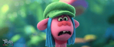 A Troll Wearing A Green Hat And Blue Hair Is Making A Funny Face . GIF