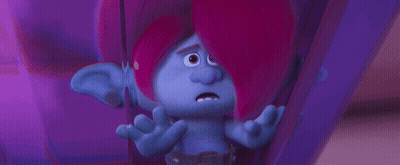 A Troll With Pink Hair And Blue Ears Is Sitting In A Purple Room . GIF
