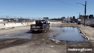 A Truck Is Driving Through A Muddy Puddle With Make A Gif.com At The Bottom Of The Screen GIF