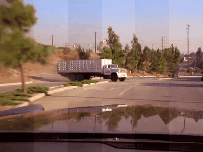 A Truck With A Fence On The Back Is Driving Down The Road GIF