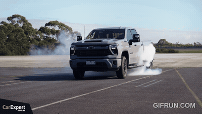 A Truck With Smoke Coming Out Of The Tires Is Driving Down A Road With A Car Expert Logo In The Corner GIF