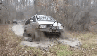 A Van Is Driving Through A Muddy Area With Trees In The Background GIF