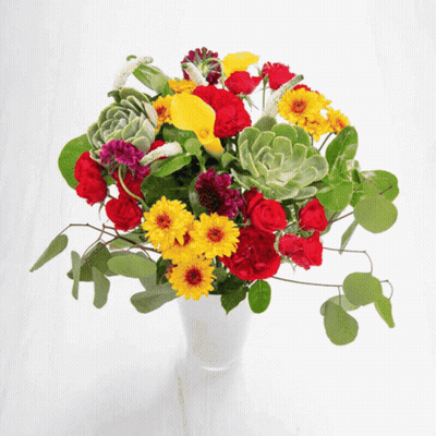 A Vase Filled With Flowers And Succulents On A White Surface GIF