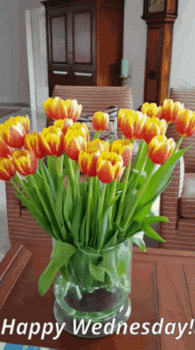A Vase Filled With Orange And Yellow Tulips With The Words Happy Wednesday GIF