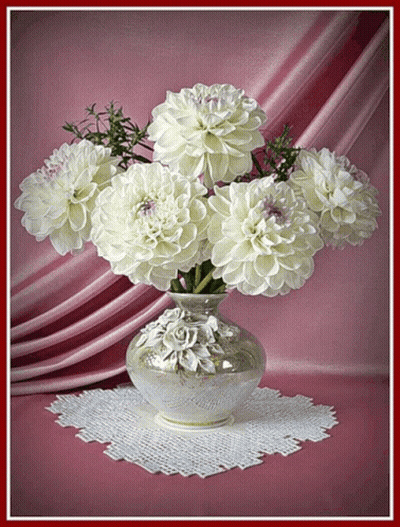 A Vase Filled With White Flowers Is Sitting On A Table GIF
