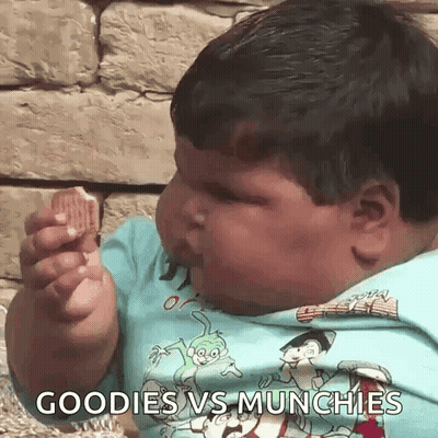 A Very Fat Boy Is Eating A Cookie With The Words Goodies Vs Munchies Written On His Shirt . GIF