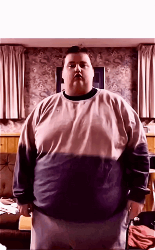 A Very Fat Man Standing In Front Of A Wall With Curtains GIF