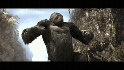 A Very Large Gorilla Is Standing On A Rocky Hillside GIF