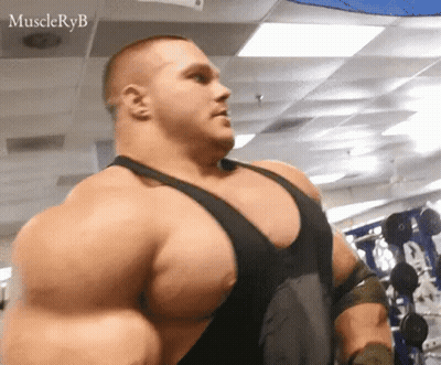 A Very Large Man Is Standing In A Gym With A Lot Of Muscles . GIF