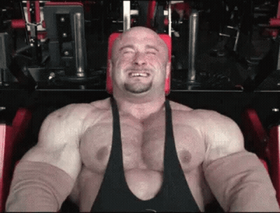 A Very Muscular Man Is Sitting On A Machine In A Gym . GIF