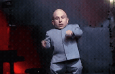 A Very Small Man In A Suit Is Dancing In Front Of A Piano . GIF