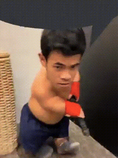 A Very Small Man Is Wearing Boxing Gloves And Sitting On A Bed GIF