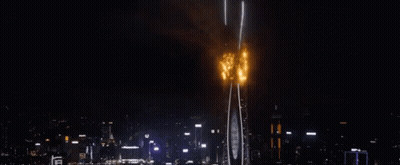 A Very Tall Building Is On Fire In The Middle Of The Night . GIF