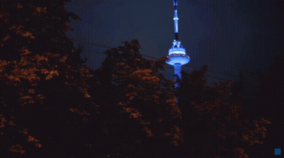 A Very Tall Tower Is Lit Up With Blue Lights GIF