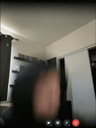 A Video Call Is Taking Place In A Room With A Person 'S Hand In The Foreground GIF