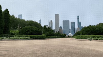 A View Of A City Skyline From A Park With Trees In The Foreground GIF